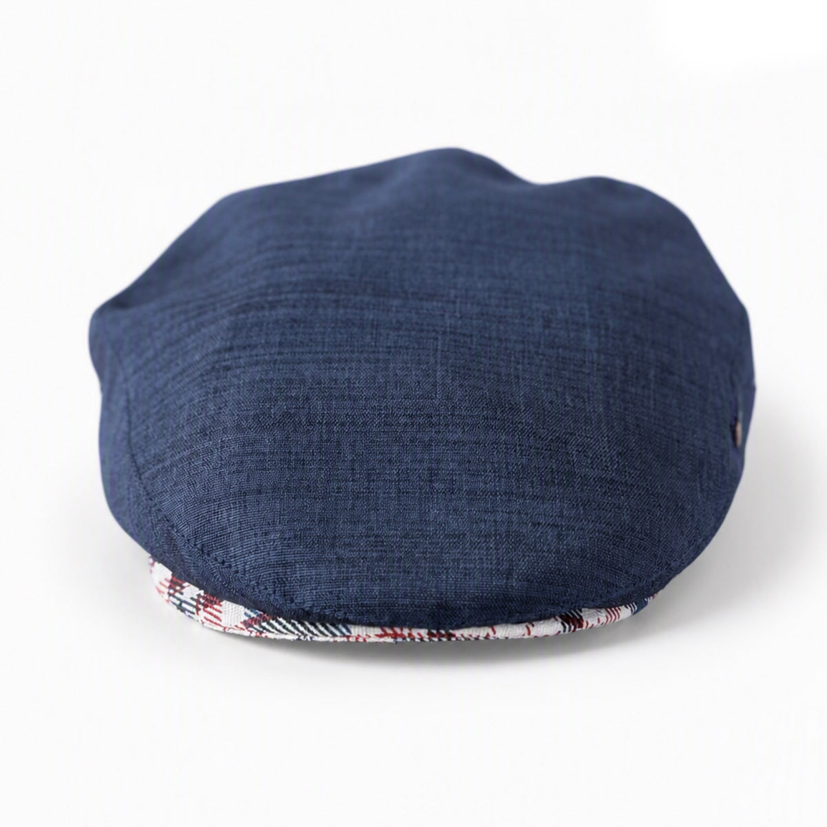 A navy blue textured fabric flat cap in front of a white background, with a patterned red, white, and blue brim lining visible underneath.
