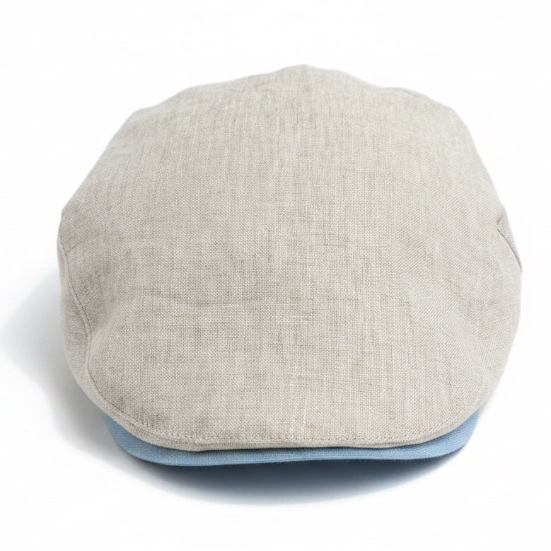 A light beige linen flat cap with a light blue underside, photographed from the front on a white background 
