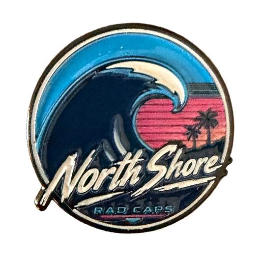 A circular enamel pin featuring a stylized wave graphic with the words 'North Shore' and 'RAD CAPS' on a white background 